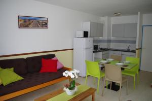 Una sala de estar con un sofá y una mesa y una cocina. en Village Club Thalassa, en Mèze