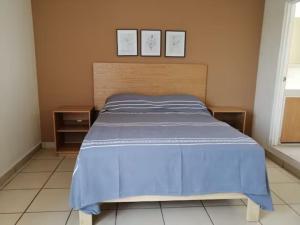 um quarto com uma cama azul com duas fotografias na parede em Departamento Ledu 204 em Morelia