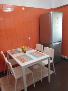 a kitchen with a table with chairs and a refrigerator at Apartament SAGA in Suceava