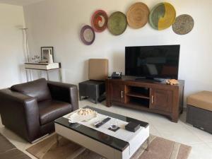 a living room with a leather chair and a television at Relaxing 2 Bed Apartment with pool view Sol Dunas in Prainha