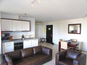 a living room with a brown couch and a kitchen at Relaxing 2 Bed Apartment with pool view Sol Dunas in Prainha