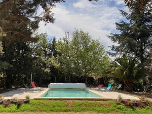 a swimming pool in a yard with chairs and trees at Chambres d'hôtes dans propriété rurale in Béziers