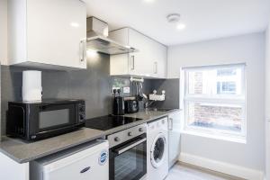 a kitchen with a microwave and a washer and dryer at Securematics Queens Studio Apartments in London