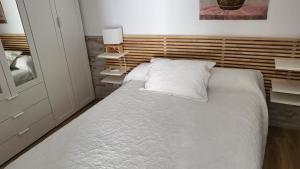 Schlafzimmer mit einem großen Bett mit einem Kopfteil aus Holz in der Unterkunft Apartamento EL REAL - Espartinas - SEVILLA in Espartinas