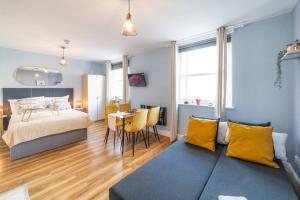 1 dormitorio con cama y mesa con almohadas amarillas en [Hyde park-Notting Hill] London Studio Apartment en Londres