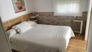 ein Schlafzimmer mit einem Bett und einer Ziegelwand in der Unterkunft Apartamento EL REAL - Espartinas - SEVILLA in Espartinas