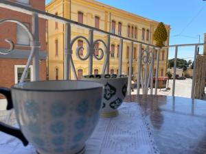 dos tazas sentadas en una mesa frente a un edificio en La Casa di Vicolo Re, Vicino alla Scala dei Turchi en Porto Empedocle