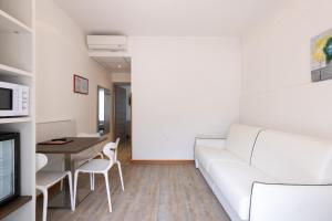 ein Wohnzimmer mit einem weißen Sofa und einem Tisch in der Unterkunft Park Hotel Val Di Monte ***S in Malcesine
