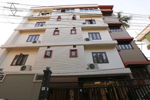 a tall white building with red windows at Niharika Guest House in Guwahati