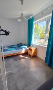 1 dormitorio con 1 cama y una ventana con cortinas azules en #WilkasyPortPlaża, en Wilkasy