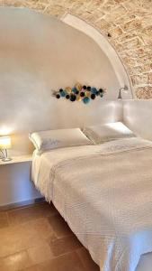 1 dormitorio con cama blanca y pared de piedra en Dimora Luglio 1651, en Ostuni