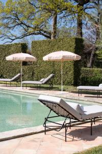 three chairs and umbrellas next to a swimming pool at Domaine de Chalamon in Saint-Rémy-de-Provence