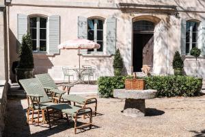 a group of chairs and an umbrella in front of a building at Domaine de Chalamon in Saint-Rémy-de-Provence