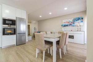 uma cozinha e sala de jantar com uma mesa e cadeiras brancas em Sunshine Apartment - Modern Ap Near the Beach em Viana do Castelo mais 15 fotografias