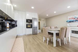 a kitchen and dining room with a white table and chairs at Sunshine Apartment - Modern Ap Near the Beach in Viana do Castelo
