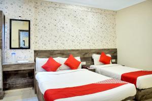 sypialnia z 2 łóżkami z czerwonymi poduszkami i lustrem w obiekcie OYO Rana Residency Near Western Express Highway Metro Station w Bombaju