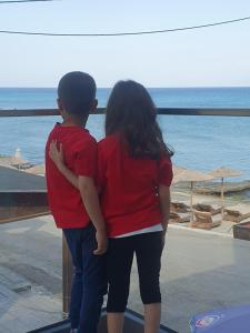 Un ragazzo e una ragazza che guardano l'oceano di Sandy feet comfort suite a Kardámaina