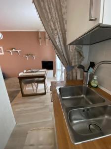 une cuisine avec un évier en acier inoxydable et une table dans l'établissement Appartamento Chagall, à Asti