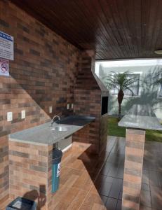 a kitchen with a sink and a brick wall at Apartamento novo wi-fi + TV in Ponta Grossa