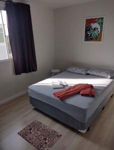 a bedroom with a bed with a red towel on it at Apartamento novo wi-fi + TV in Ponta Grossa