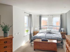 a bedroom with a bed and a table and windows at Heddfan in Llanelli