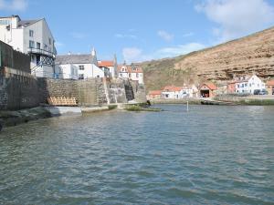 a body of water with buildings and houses on a hill at Thistle-doo Nicely in Staithes