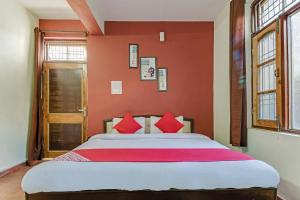 a bedroom with a large bed with red walls at OYO Twilight Guest House in Banikhet