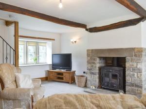 sala de estar con chimenea y TV en Higher Kirkstall Wood Farm en Ingrow