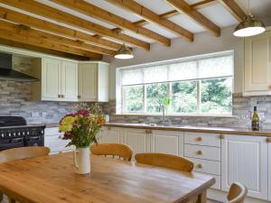 una cocina con una mesa de madera con un jarrón de flores. en Higher Kirkstall Wood Farm en Ingrow