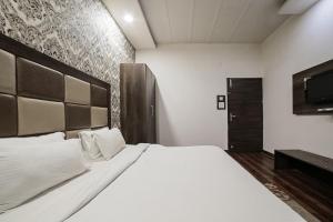 - une chambre avec un grand lit blanc et une télévision dans l'établissement Super Townhouse 561 Hotel Hollywood Heights, à Amritsar