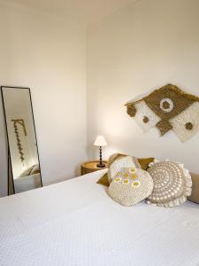 um quarto com uma cama branca com almofadas e um espelho em Prad'Arte em Santarém