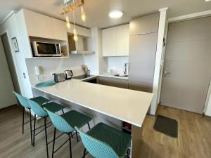 una cocina con encimera blanca y sillas. en Confortable y Centrico Depto Papudo, en Papudo