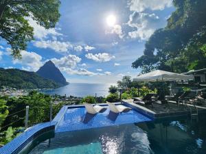 a swimming pool with chairs and a view of the water at Green Fig Resort & Spa in Soufrière