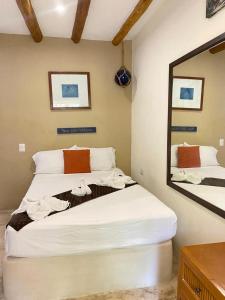 1 dormitorio con 2 camas y espejo en La Constanza de Rulo en Holbox Island