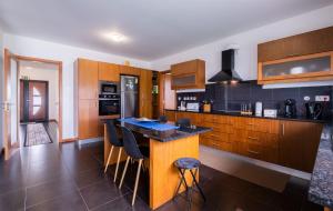 a kitchen with wooden cabinets and a island with bar stools at Azores Mountain View in Ribeira Grande