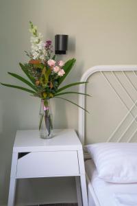 een vaas met bloemen op een tafel naast een bed bij Tulipán Apartman in Eger