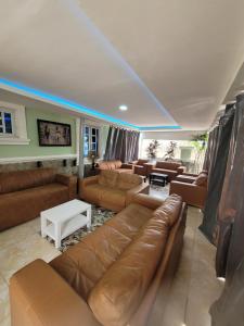 a living room with brown leather couches and a white table at Dazzle Hotels and Apartments in Jidu