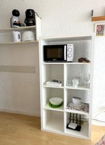 a white shelf with a microwave on top of it at Studios LES TERRASSES de Cala Llevado in Tossa de Mar