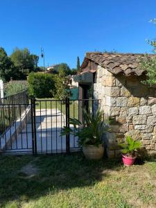 un portail avec des plantes devant un mur en pierre dans l'établissement jolie appartement avec piscine, à La Roquette-sur-Siagne