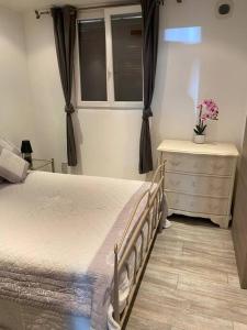 a bedroom with a bed and a dresser and a window at jolie appartement avec piscine in La Roquette-sur-Siagne