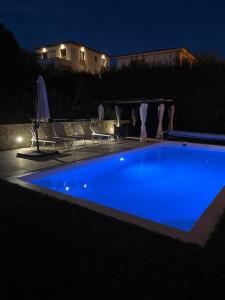 - une piscine bleue la nuit avec des chaises et un bâtiment dans l'établissement jolie appartement avec piscine, à La Roquette-sur-Siagne