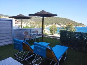 a balcony with chairs and tables and an umbrella at New Aegli Resort Hotel in Poros