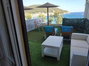 einen Balkon mit Stühlen, einem Tisch und einem Sonnenschirm in der Unterkunft New Aegli Resort Hotel in Poros