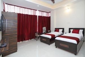 two beds in a room with red curtains at Super Hotel O Royal Inn in Faridabad