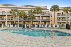 a swimming pool in front of a hotel with palm trees at Endless Summer by Panhandle Getaways in Panama City Beach