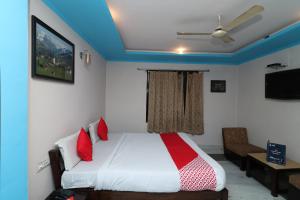1 dormitorio con cama blanca y almohadas rojas en OYO 13161 Apni Havali Hotel & Restaurant, en Rāmpura