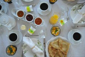 a table with plates of food and cups of coffee at Demeure de kergoguen in Plougonver +8 photos