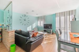 a living room with a couch and a clock on the wall at Vivienda Turística Portal de Teruel in Teruel