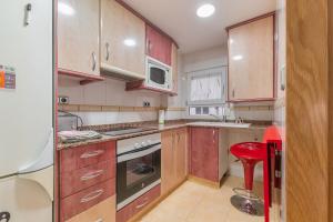 a kitchen with wooden cabinets and a red stool in it at Vivienda Turística Portal de Teruel in Teruel
