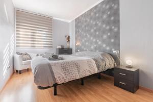 a bedroom with a large bed and a chair at Vivienda Turística Portal de Teruel in Teruel